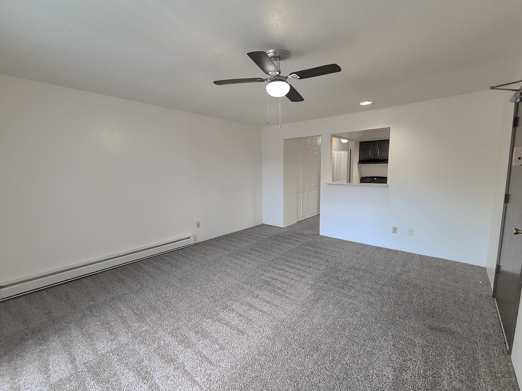 A room with a ceiling fan and carpeted floor.