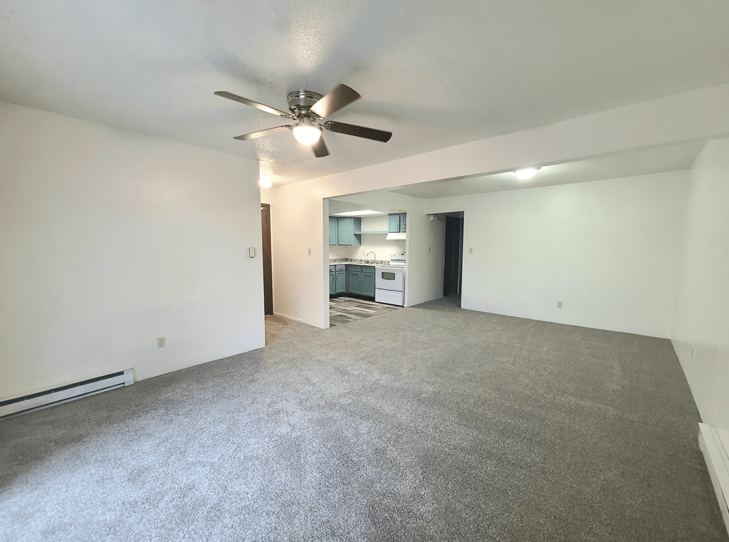 A spacious room with a ceiling fan and carpeted floor.