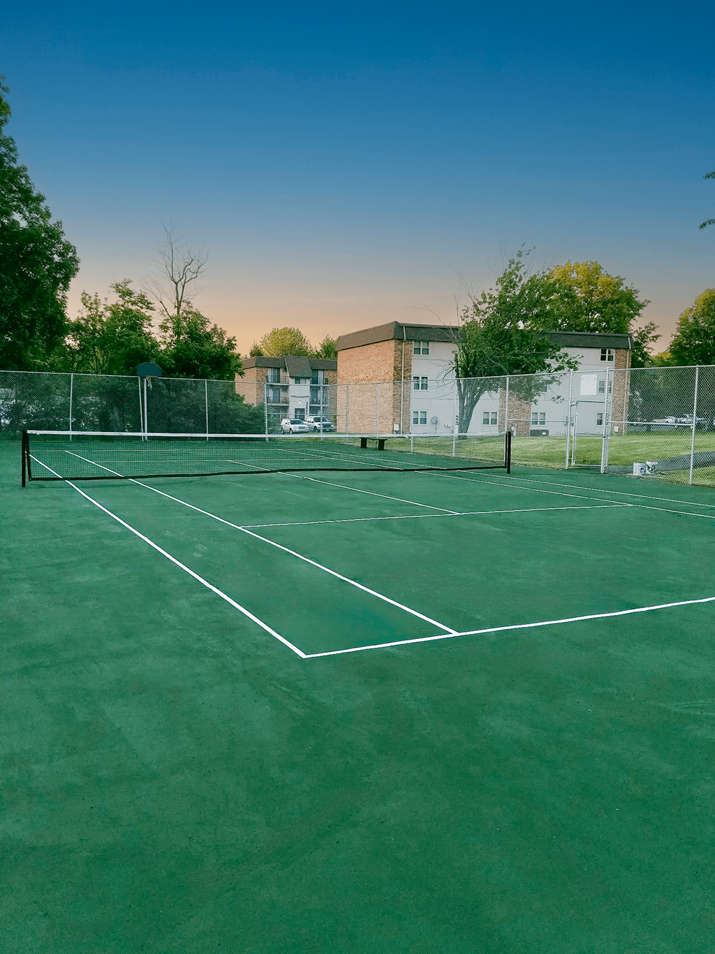 A tennis court with white lines on a green surface.