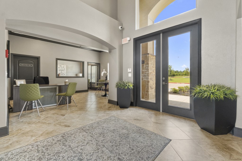 a lobby with glass doors and a table with chairs and a rug