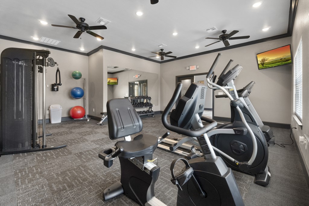 a gym with exercise equipment and ceiling fans