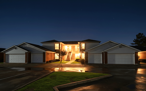 A house with a garage is illuminated from the inside.