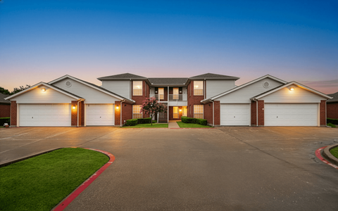 A row of houses with garages are shown at dusk.