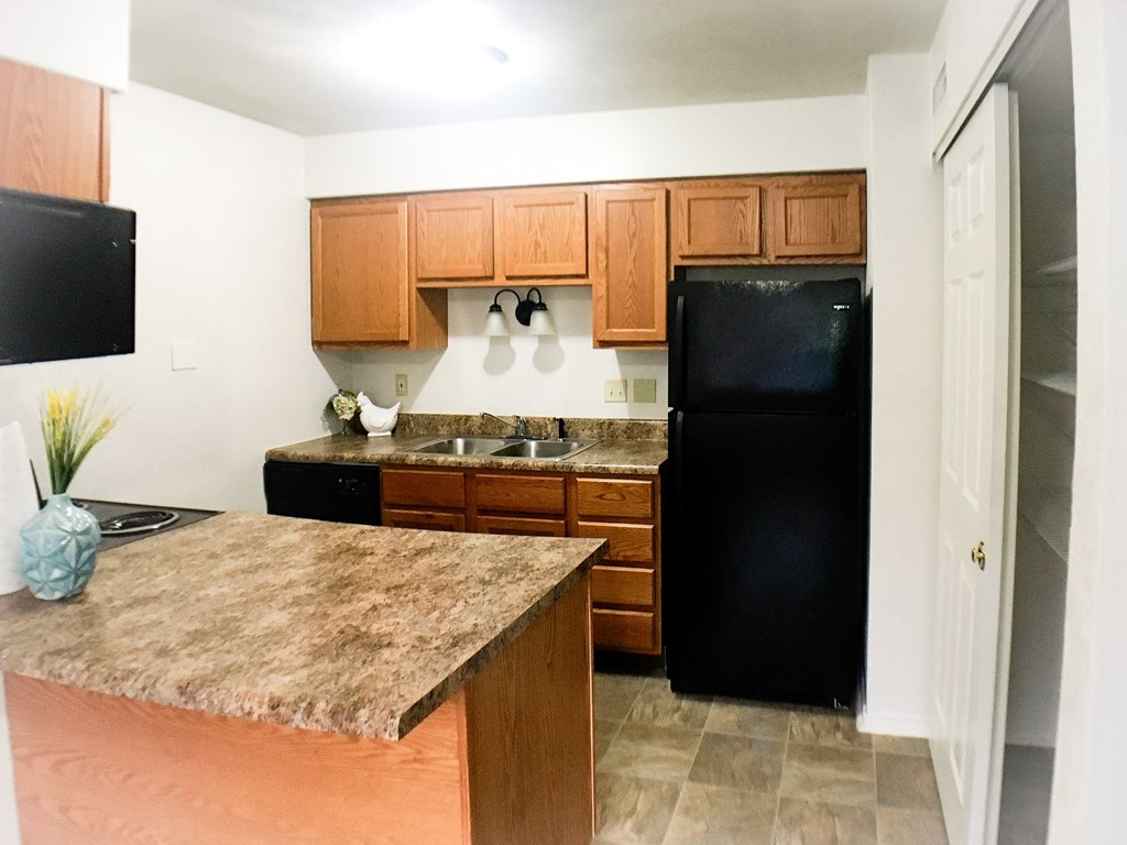 a kitchen with black appliances and wooden cabinets and a marble counter top