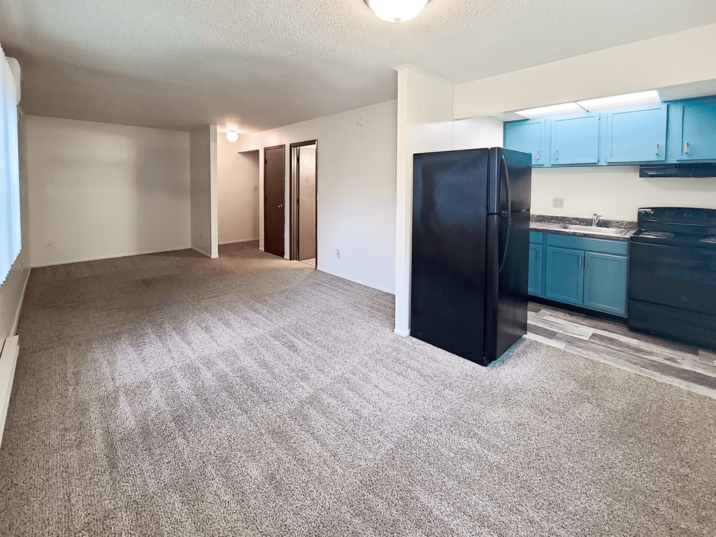 A black refrigerator sits in a kitchen with blue cabinets.