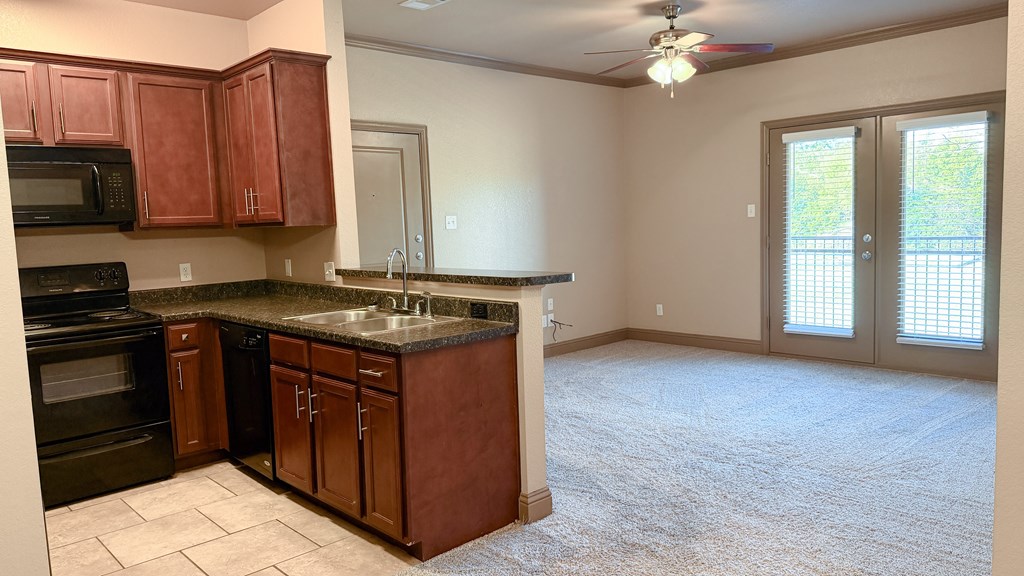 A kitchen with brown cabinets and a black oven.