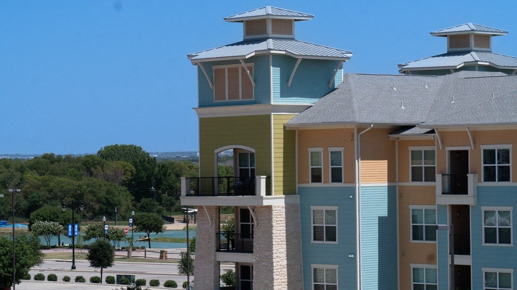 a large apartment building with two balconies and a large body of water in the background
