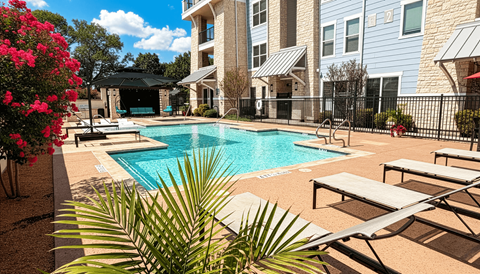 A pool surrounded by lounge chairs and a fence.