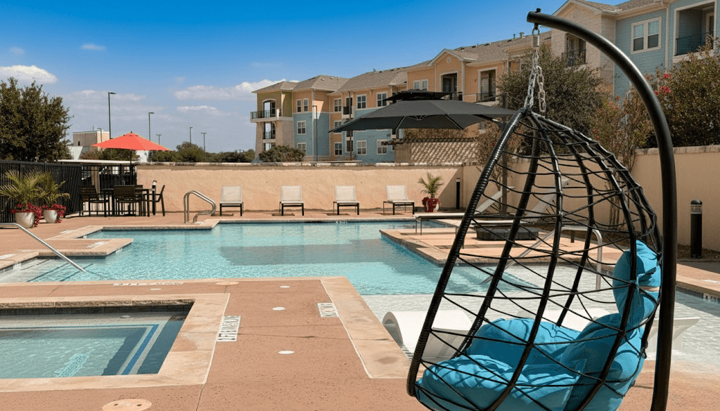 A black hanging chair is in the foreground of a pool area.