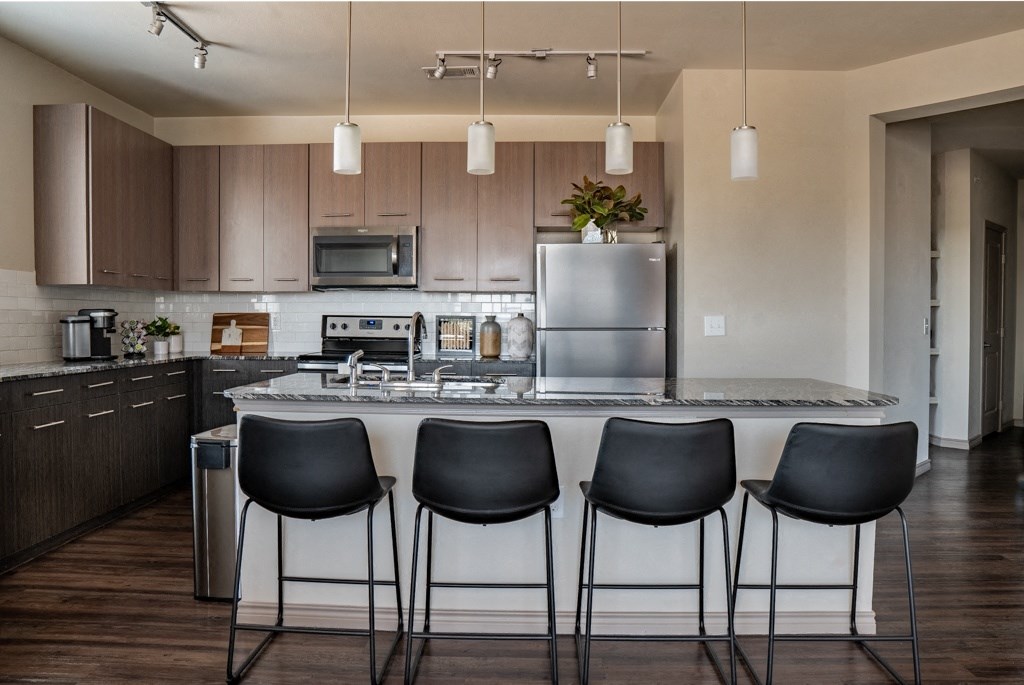 a kitchen with a large island with four chairs around it