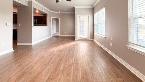A spacious room with wooden flooring and a ceiling fan.