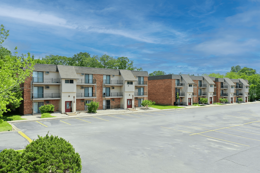 A row of apartment buildings with a parking lot in front.