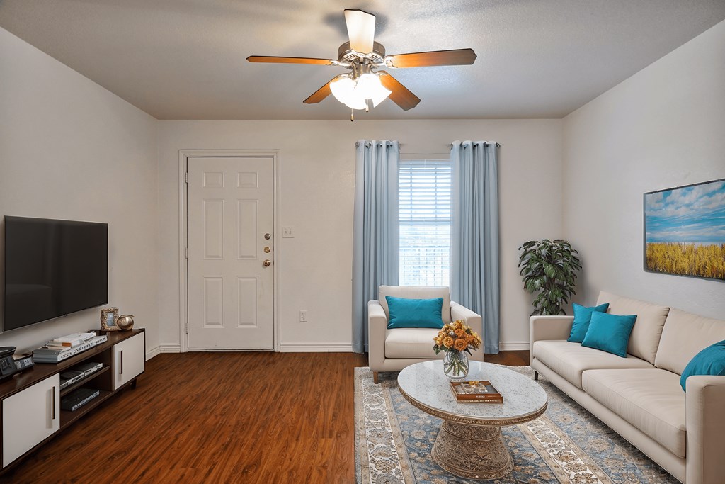 A living room with a white couch, a coffee table, a ceiling fan, and a painting on the wall.