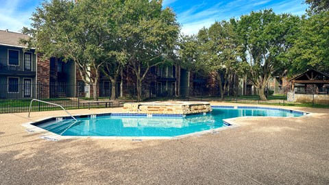 a swimming pool with a fence and apartment buildings in the background
