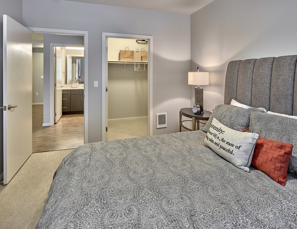 a bedroom with a large bed, closet, and a bathroom with a mirror