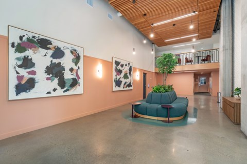 A large artwork hangs on a wall above a green couch in a spacious room.