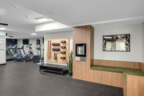 A gym with a variety of equipment including treadmills, stationary bikes, and weights.