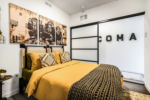 a bedroom with a bed with a yellow comforter and pillows and a black and