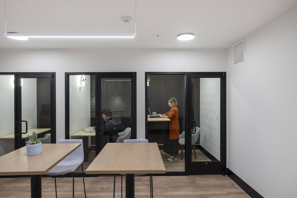 a woman standing at a desk in a room with tables