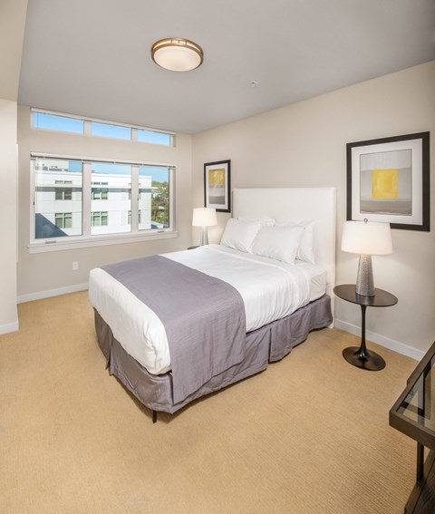 Bedroom with white upholstered headboard and natural light at The Lyric Apartments, Seattle, WA