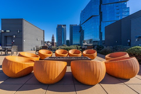 a lounge area with orange chairs and a table in front of tall buildings