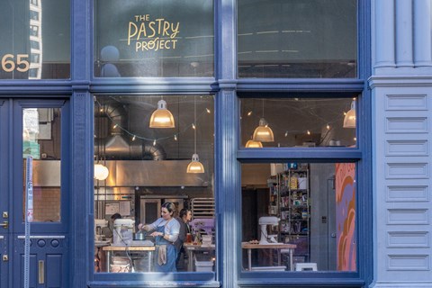 a woman stands in the window of a pastry shop