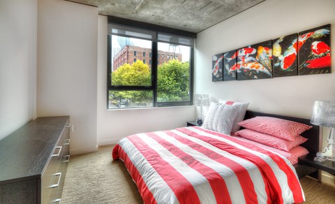 a bedroom with a red and white bed and a window