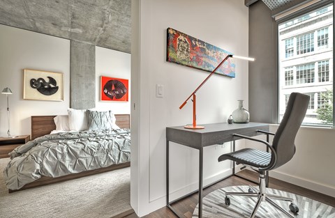 a bedroom with a bed and a desk with a chair and a lamp