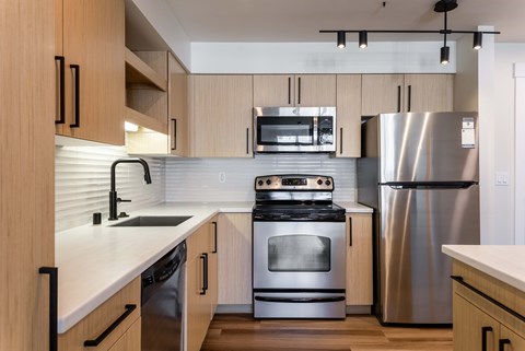 A modern kitchen with wooden cabinets and stainless steel appliances.