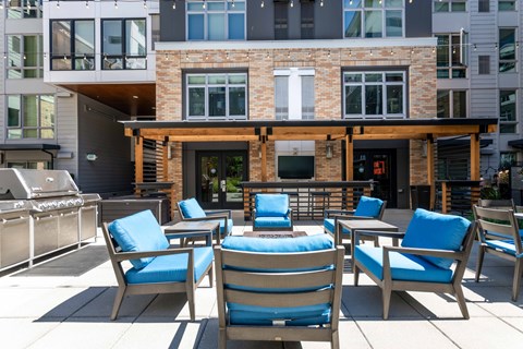 A patio with blue chairs and a table with a blue cushion.