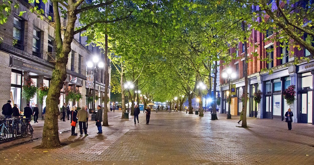 people walking down a tree lined street at night