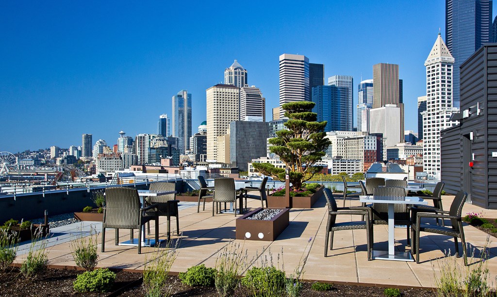 a rooftop terrace with tables and chairs overlooking the skyline