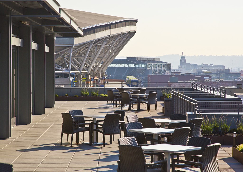 a terrace with tables and chairs and a view of a stadium and a city