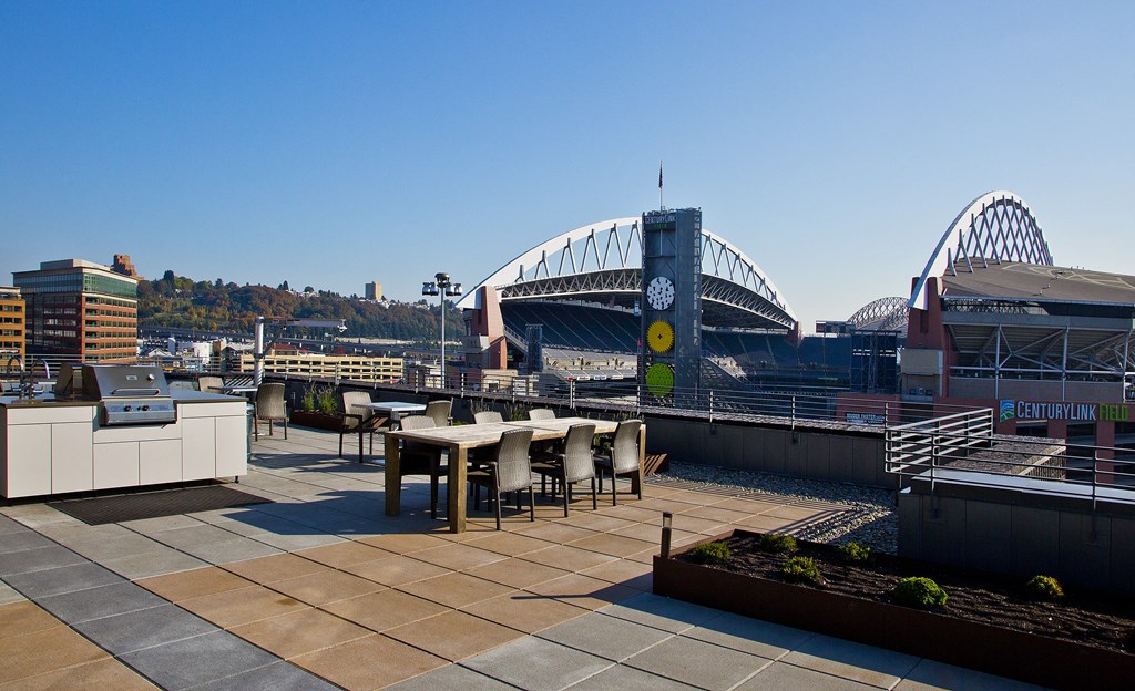 a rooftop terrace with a view of the sydney harbour bridge and stadium