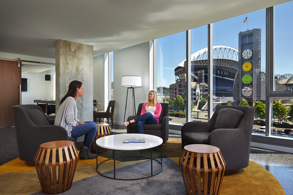 two women sit in a living room with a view of the stadium