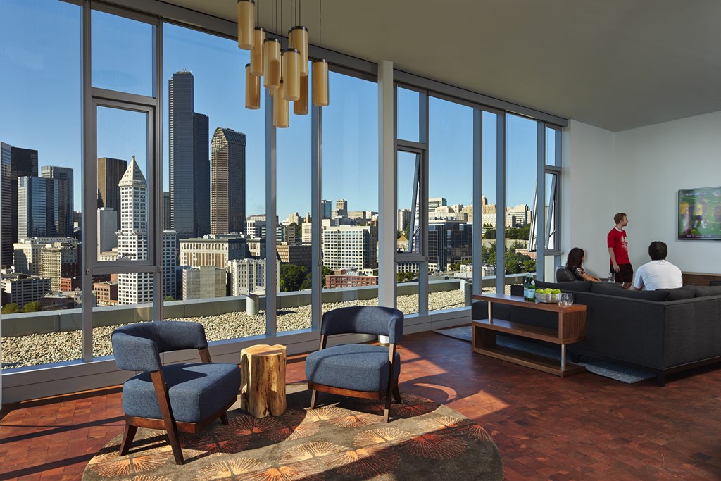 a view of the city skyline from a living room with a couch and chairs
