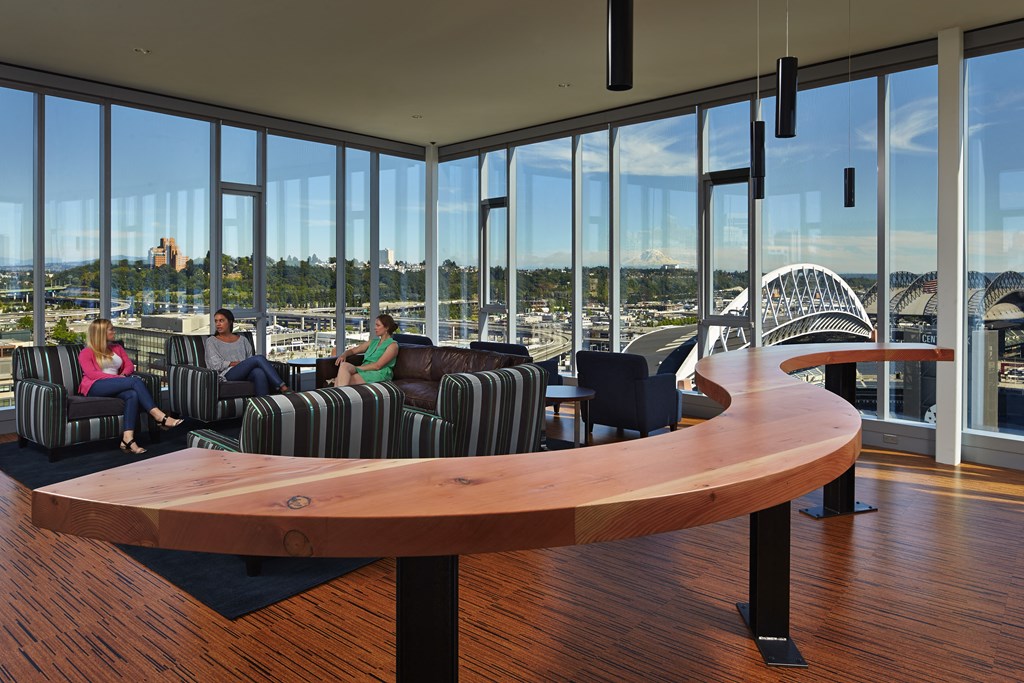 people sit in a living room with a table and views of a bridge