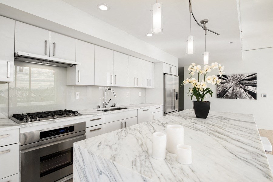 a large kitchen with marble counter tops and white cabinets