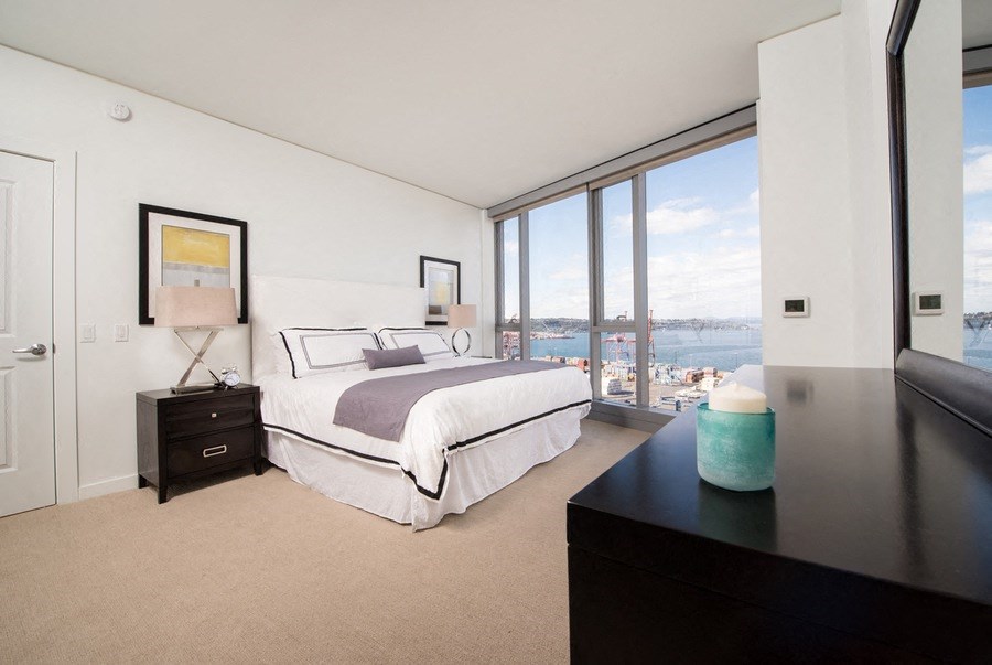 the master bedroom has a view of the water and a large bed and a window