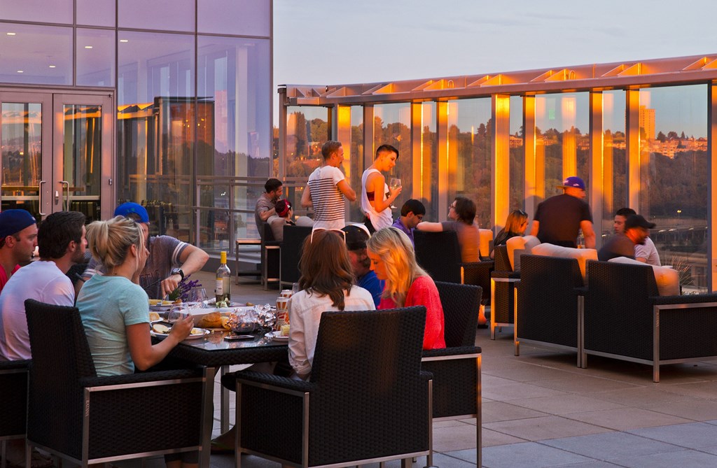 a group of people sitting at tables on a rooftop restaurant