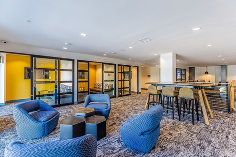 A modern living room with blue chairs and a grey rug.