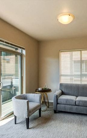 A living room with a grey couch, a chair, and a small table at The Corydon, Washington