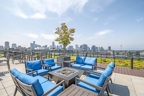 A patio with blue cushions and a table with a tree in the background.
