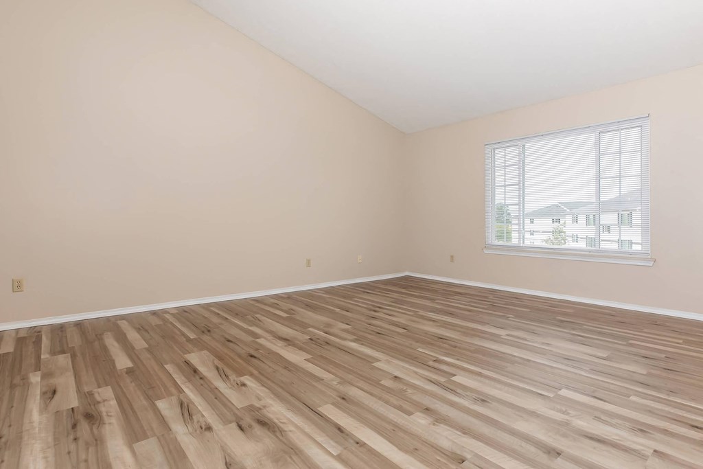 an empty room with a window and wood floors
