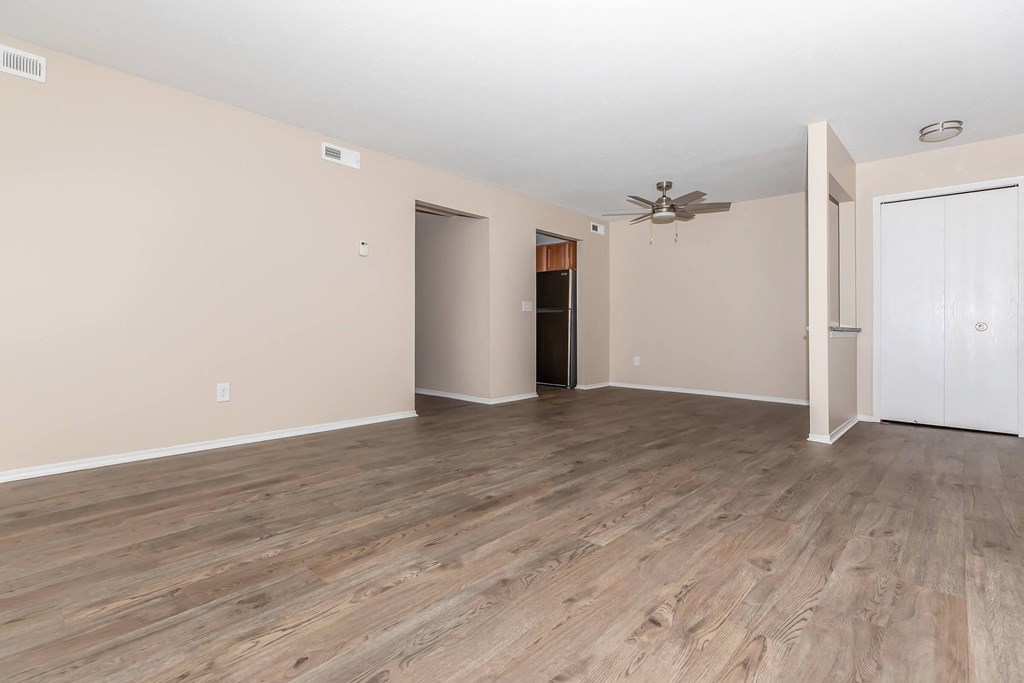 an empty living room with wood floors and a ceiling fan