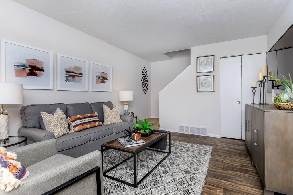 A living room with a grey couch, a coffee table, and pictures on the wall.