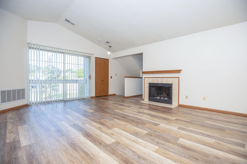 an empty living room with a fireplace and a sliding glass door
