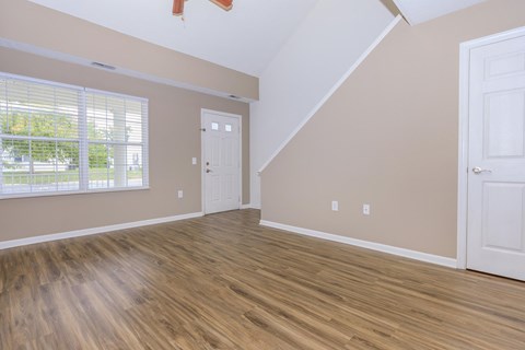 an empty living room with wood flooring and a window