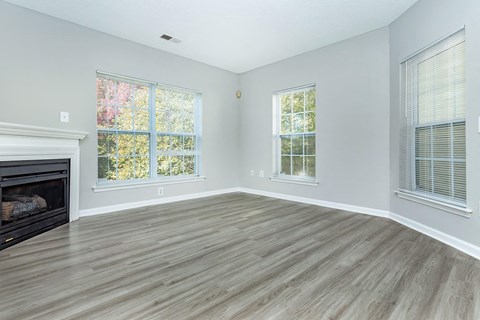 an empty living room with a fireplace and windows