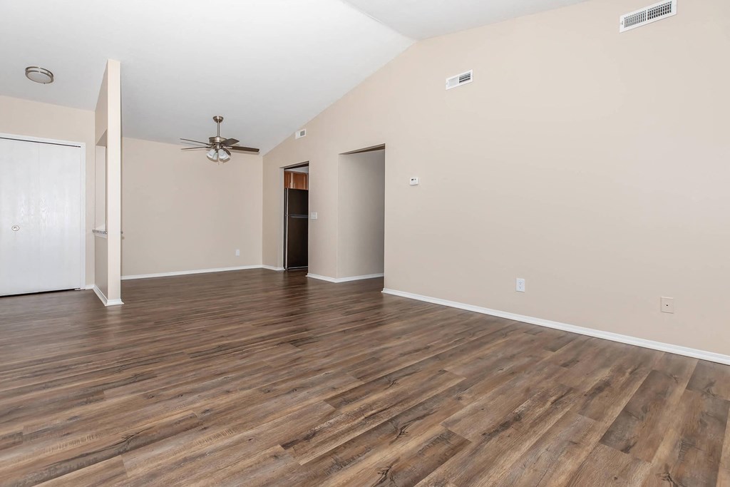 an empty living room with hard wood floors and a ceiling fan